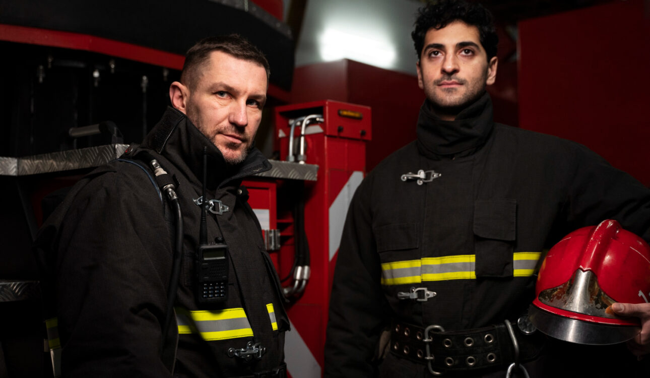Two firefighters in full gear standing inside a fire station, representing first responders affected by low testosterone in Hackensack NJ.