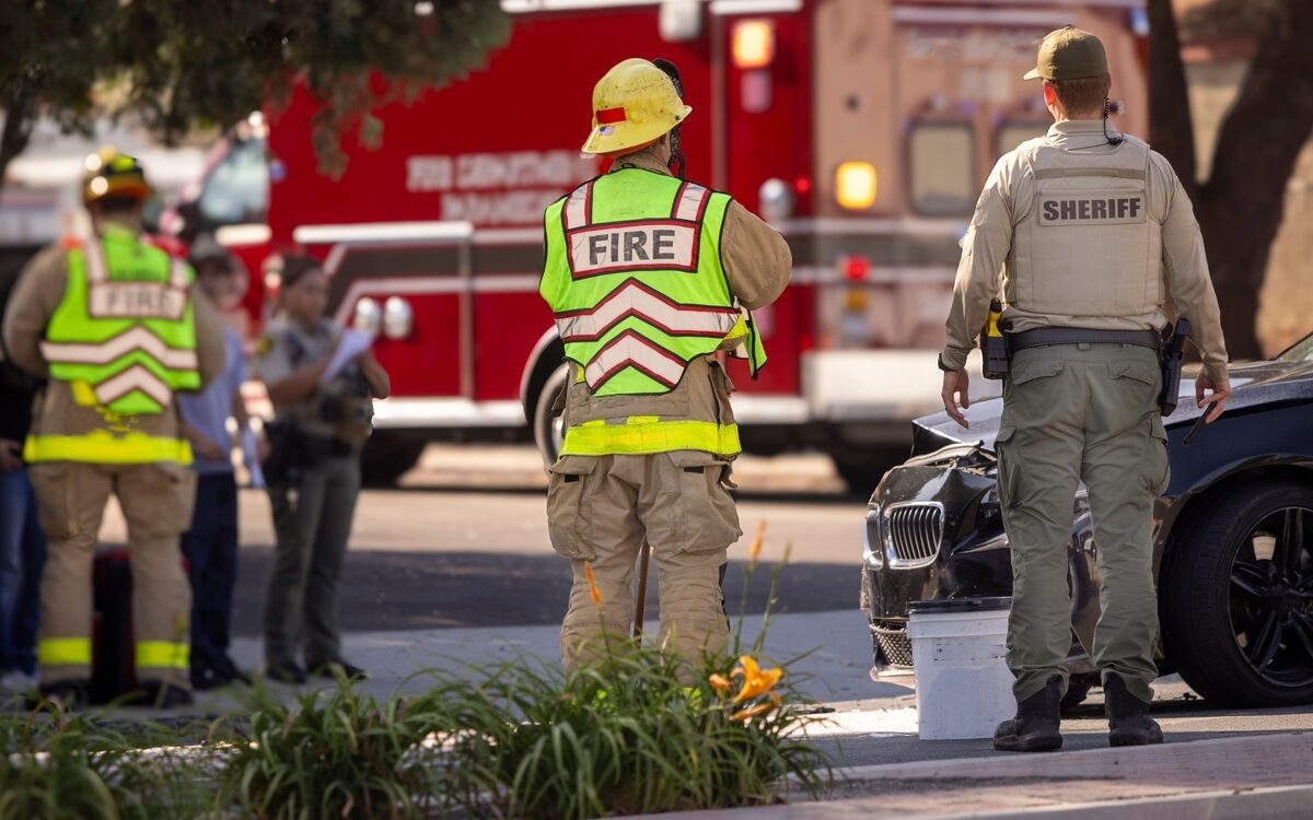 Firefighters and sheriff's deputy standing at an accident scene, representing occupational risk factors for varicose veins in first responders