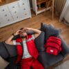 EMS worker experiencing chronic pain in first responders off duty lying exhausted on couch after shift