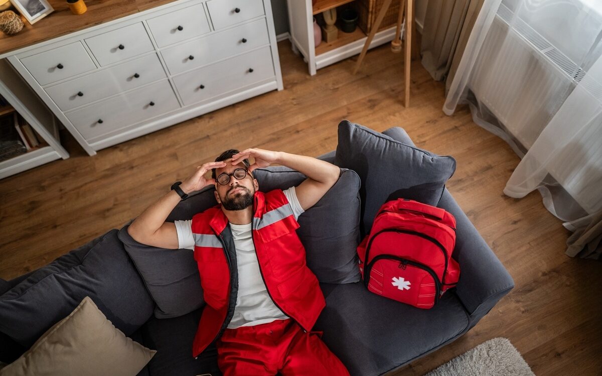 EMS worker experiencing chronic pain in first responders off duty lying exhausted on couch after shift
